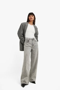Gray oversized blazer, white fitted top, high-waisted gray baggy jeans, and black pointed-toe heels; plain textures, minimal detailing.