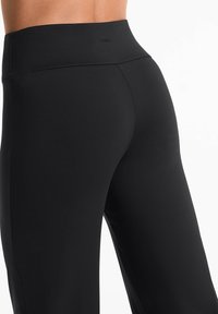 Schwarze Leggings mit hohem Taillenbund, aus glattem, dehnbarem Stoff gefertigt. Verfügt über ein minimalistisches Design ohne sichtbare Logos oder Muster.
