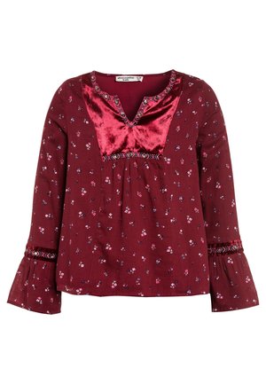 Mädchenbluse in Dunkelrot mit langen Ärmeln, kleinem Blumenmuster, rotem Samt-Übertritt, bestickten Details und ausgestellten Manschetten.