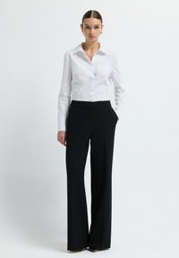 Witte button-up blouse met een kraag, gecombineerd met hoge zwarte wijde broek. Glad materiaal met een nette, op maat gemaakte pasvorm.