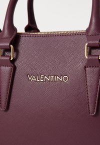 Burgundy handbag with a textured surface, gold-tone hardware, and a prominent "VALENTINO" logo. Features dual top handles for carrying.