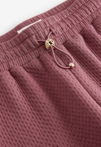 Lila texturerade shorts med elastisk midja, som har en dragsko med en guldfärgad toggel och subtila sydda detaljer.