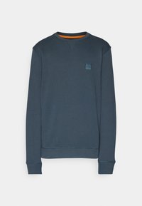 Sweat-shirt bleu marine à manches longues et col rond, avec une petite écusson logo carré sur la poitrine gauche et une doublure orange à l'intérieur du col.