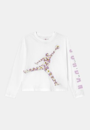 Camiseta blanca de manga larga con un gráfico floral de una figura saltando y la palabra "JORDAN" impresa en púrpura en la manga. Material de algodón suave.