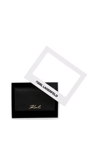 Fekete bőr Karl Lagerfeld pénztárca egy nyitott fehér dobozban, amelynek levehető fedője logóval díszítve, fehér háttér előtt.