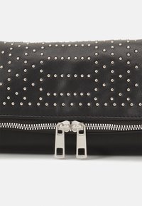Clutch in pelle nera con borchie argentate disposte in un motivo a griglia, dotato di chiusura a zip argentata con due linguette di apertura sul bordo inferiore.