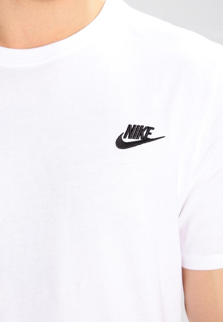 Bílý bavlněný tričko s krátkými rukávy a kulatým výstřihem, s malým černým vyšívaným logem Nike na levé části hrudi.