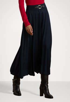 Flowy black skirt with a high waist, featuring a wide belt with gold hardware. Paired with knee-high black leather boots.