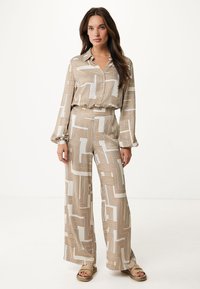 Completo a due pezzi composto da una blusa a fantasia e pantaloni a gamba larga in crema con linee geometriche dorate. Tessuto morbido e vestibilità rilassata.