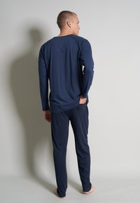 Marineblaues Langarmshirt und passende Hose, aus weichem Material. Das Shirt hat einen Rundhalsausschnitt und die Hose verfügt über Taschen.