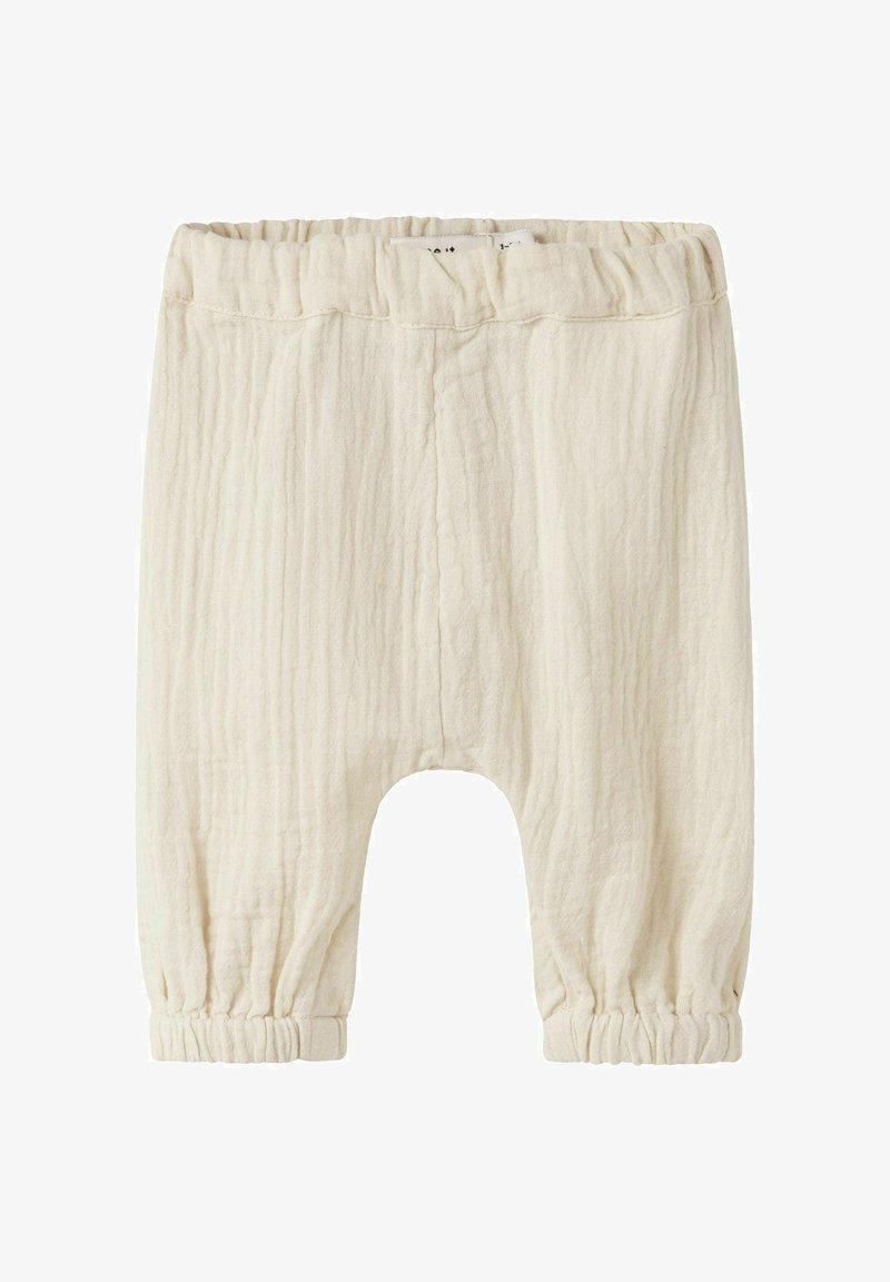 Μαλακός παντελονάκι μωρού σε κρεμ χρώμα με ελαστική μέση και μανσέτες, κατασκευασμένο από υφασμάτινη υφή ελαφριάς ποιότητας.