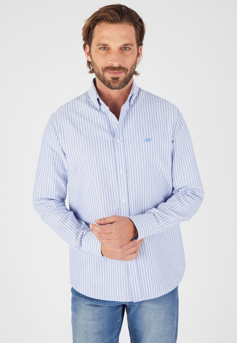 Camicia button-down a righe blu e bianche con maniche lunghe, colletto e orlo arrotondato, realizzata in un tessuto leggero misto cotone.