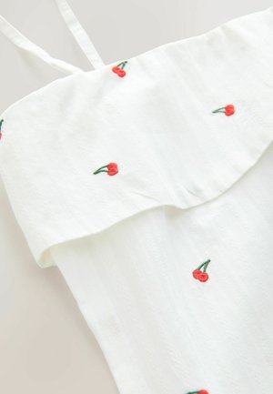 Biały top z materiału, z falbaniastym dekoltem, cienkimi ramiączkami oraz haftem czerwonych wiśni w rozproszonym wzorze. Teksturowane wykończenie.