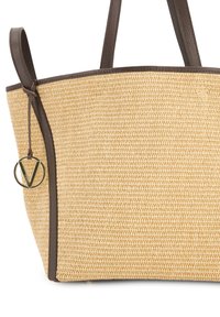 Vævet stråtosse i beige med brune læderdetaljer. Har en buet top og et rundt emblem hængende ved en snor. Letvægtsdesign.