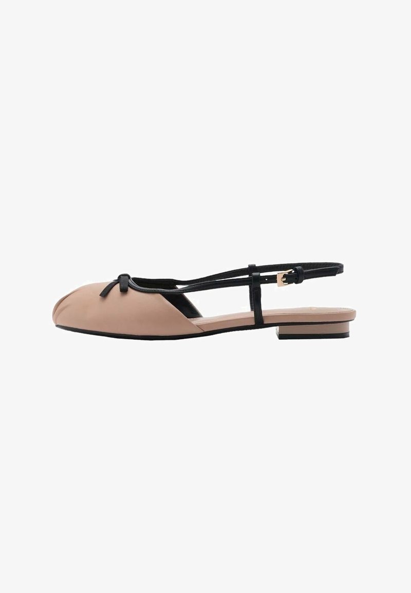 Chaussure plate beige à bout rond, avec une bride noire et un détail de nœud. Finition brillante, semelle plate et design minimaliste.