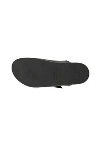 Zwarte rubberen schoenzool met een gestructureerd patroon voor grip, met een lichte kromming en een geperst logo-detail, ontworpen voor comfort en duurzaamheid.