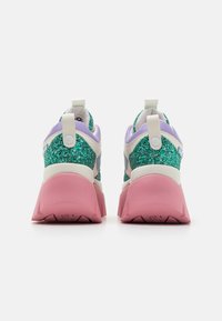 Glitrende joggesko med en grønn og hvit overdel, lilla detaljer og en rosa tykk såle. Har en dratappe bak på hælen.