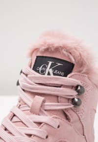 Zapatillas de ante rosa con ribete de piel sintética, parche de logo negro y ojales metálicos. Presenta cordones planos y texturizados, así como costuras reforzadas.