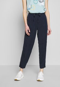 Marine casual broeken met een elastische taille en tapse pijpen, voorzien van zijzakken. Gepaard met een lichtblauw mouwloos top met kleurrijke patroonaccenten.