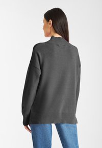 Ciemnoszary, oversize sweter z prążkowanym kołnierzem i dołem, z opadającymi ramionami. Miękka faktura i luźny krój. Styl casual.