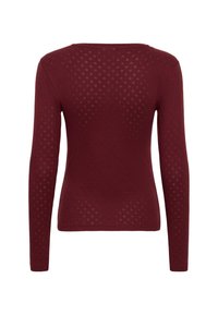 Maroon long-sleeve top with a textured pattern featuring diamond-like cutouts. Soft material with a round neckline and fitted shape.
