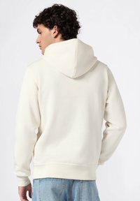 Hoodie à col ras du cou de couleur crème, fabriqué à partir d'un tissu doux. Présente une grande capuche, des poignets et un ourlet côtelés, avec une coupe décontractée.