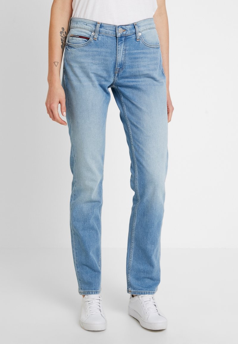Ljust blå denimjeans med rak passform, fem fickor och knappstängning. Det slitna utseendet vid knäna förbättrar detaljen.