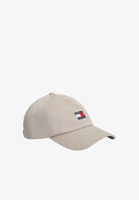 Gorra de béisbol beige con visera curva que presenta un pequeño parche rectangular con un logo en rojo, blanco y azul con el texto "Tommy Jeans".