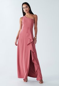 Abito monospalla rosa cipria in tessuto liscio, con balza laterale e spacco alto sulla coscia per un dettaglio in più.