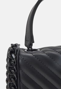 Svart vadderad handväska med en texturerad läderyta, framträdande kedjedetaljer och ett smäcker handtag för enkel bärning.