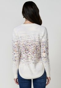Pulover alb din tricot, cu un model colorat și pistruiat, margine rotunjită și mâneci lungi. Textură moale cu manșete ribbate.