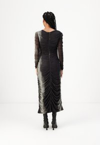 Rochie neagră cu plisaje, cu mâneci lungi din material transparent, siluetă ajustată și un efect de degradé de la nuanțe întunecate la nuanțe mai deschise. Lungime până la genunchi, cu o cusătură pe spate.
