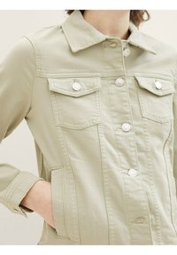 Hellgrüne Denimjacke mit durchgehendem Knopfverschluss, zwei Brusttaschen und klassischem Kragen. Akzentuiert mit silbernen Knöpfen.