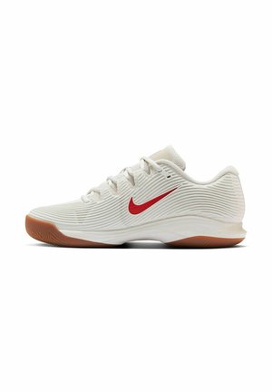 White athletic shoes with red swoosh, textured upper, lacing system, and a gum rubber outsole. Designed for performance and comfort.