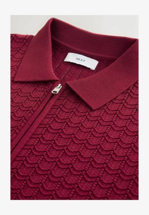 Viininpunainen neulottu poolopaita, jossa on teksturoitu aallokuvio, puoli vetoketjua edessä ja resorikaulus. Labelissa lukee "NEXT".