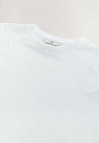 Tricou alb din bumbac cu gât rotund, mâneci scurte și textură netedă. Etichetă vizibilă la guler, cu inscripția "NEXT".