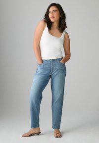 Vit åtsittande linne i kombination med ljusblå denimjeans. Jeansen har hög midja, rak benform och fickor.