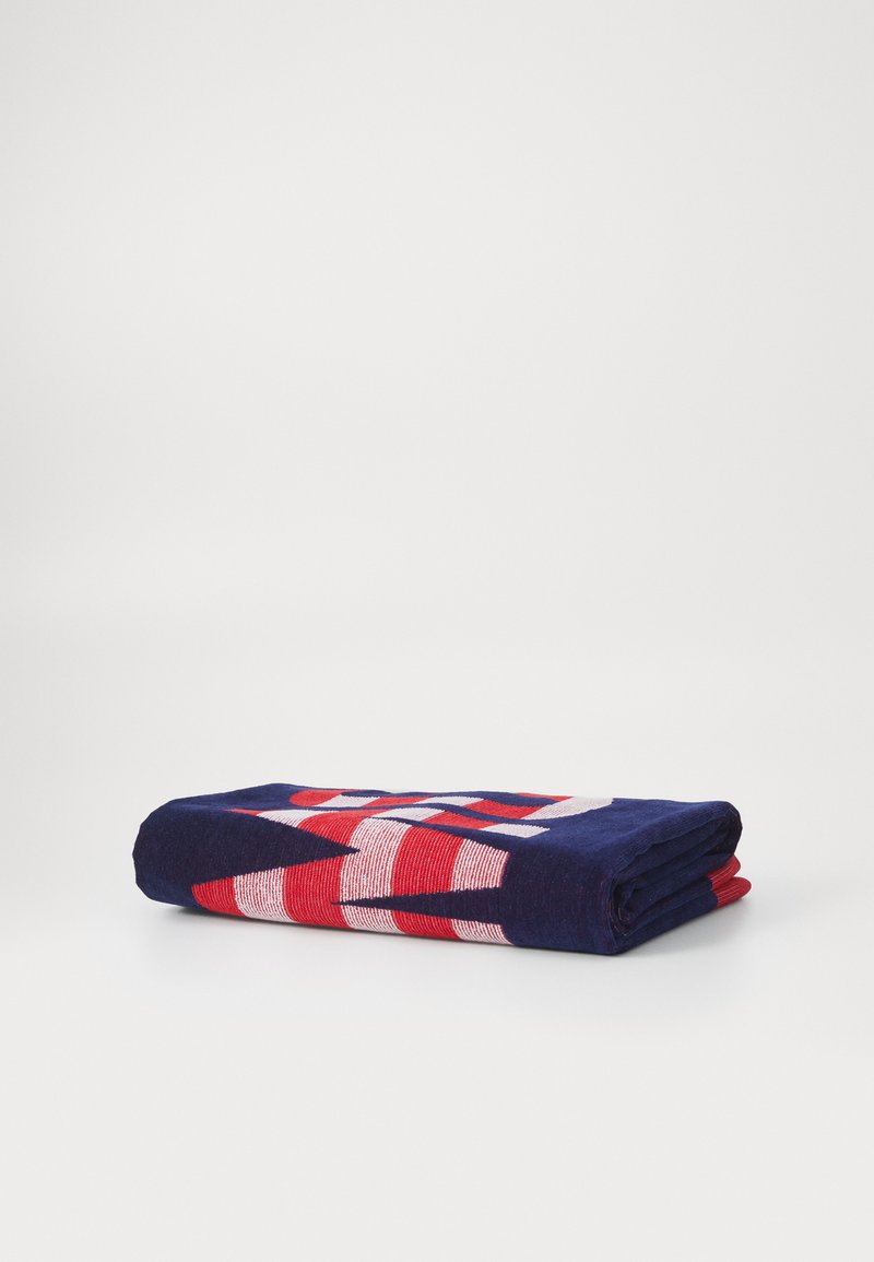 Tessuto piegato con una base blu navy e motivi geometrici rossi e bianchi. Il materiale appare morbido e tessuto.