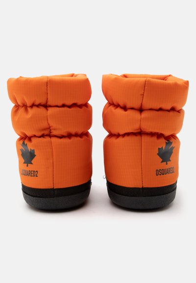 Paire de bottes d'hiver rembourrées orange avec semelles noires et logos de feuille d'érable noirs à l'arrière, sur fond blanc.