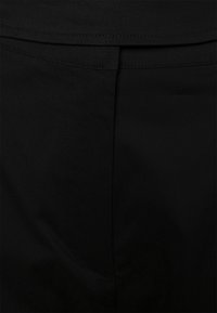 Tissu en denim noir présentant une texture lisse et un design minimaliste avec une seule poche et des coutures nettes.