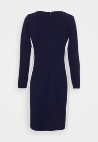 Robe longue à manches longues bleu marine avec une silhouette droite, présentant des panneaux latéraux blancs et un détail de fermeture éclair au dos. Texture de tissu lisse.