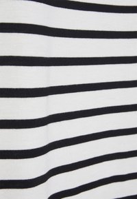 Zbliżenie na biały materiał z równomiernie rozmieszczonymi poziomymi czarnymi paskami tworzącymi wzór pasków.