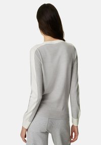 Suéter gris con detalles blancos en las mangas y puños acanalados. Textura suave y corte holgado, diseñado para la comodidad.