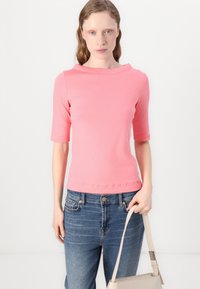 Korte mouwen roze top gemaakt van zachte stof met een rechte halslijn, gecombineerd met blauwe denim jeans en een lichte handtas.