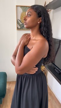 Must have ilmaõlapaelts ja kinnihoidva korpus ja laienev seelik. Modell poseerib käed rindkere lähedal kokku pandud, näidates pikki laineid juustes.