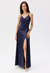 Námořnické saténové večerní šaty s těsným korzetem, tenkými ramínky, hlubokým výstřihem do V a bočním rozparkem. Mají hladkou, lesklou texturu.