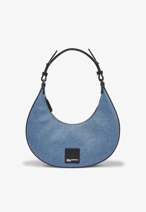 Denim skuldertaske med en buet form, ensfarvet blå farve, sorte læderdetaljer og logo-patch. Justerbar rem for tilpasselig længde.