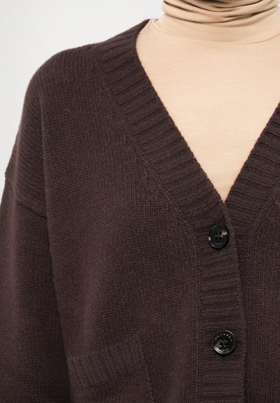 Brown knitted cardigan with a V-neck and ribbed texture. Features two front pockets and black buttons for closure.
