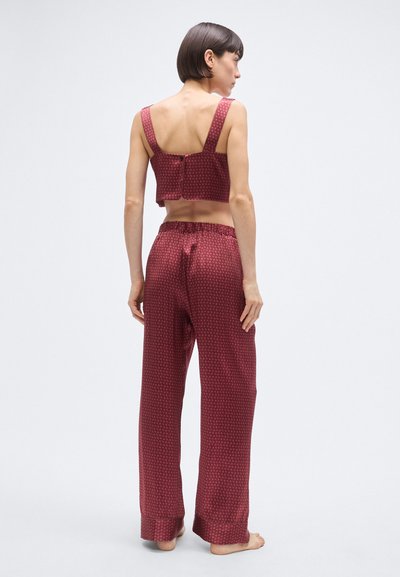 Burgundipunane pidžaamakomplekt, mis koosneb lühikesest kaunite rihmade ja nööpidega kamisolist ning lahtistest, mustrilistest pükstest, millel on elastne vöökoht.