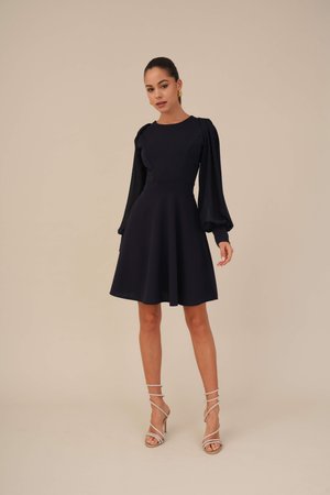 Robe bleu marine avec un corsage texturé, des manches longues bouffantes et une jupe évasée. Associée à des talons à lanières argentés. Finition en tissu lisse.